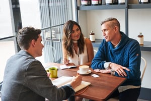 couple talking to a business man at table